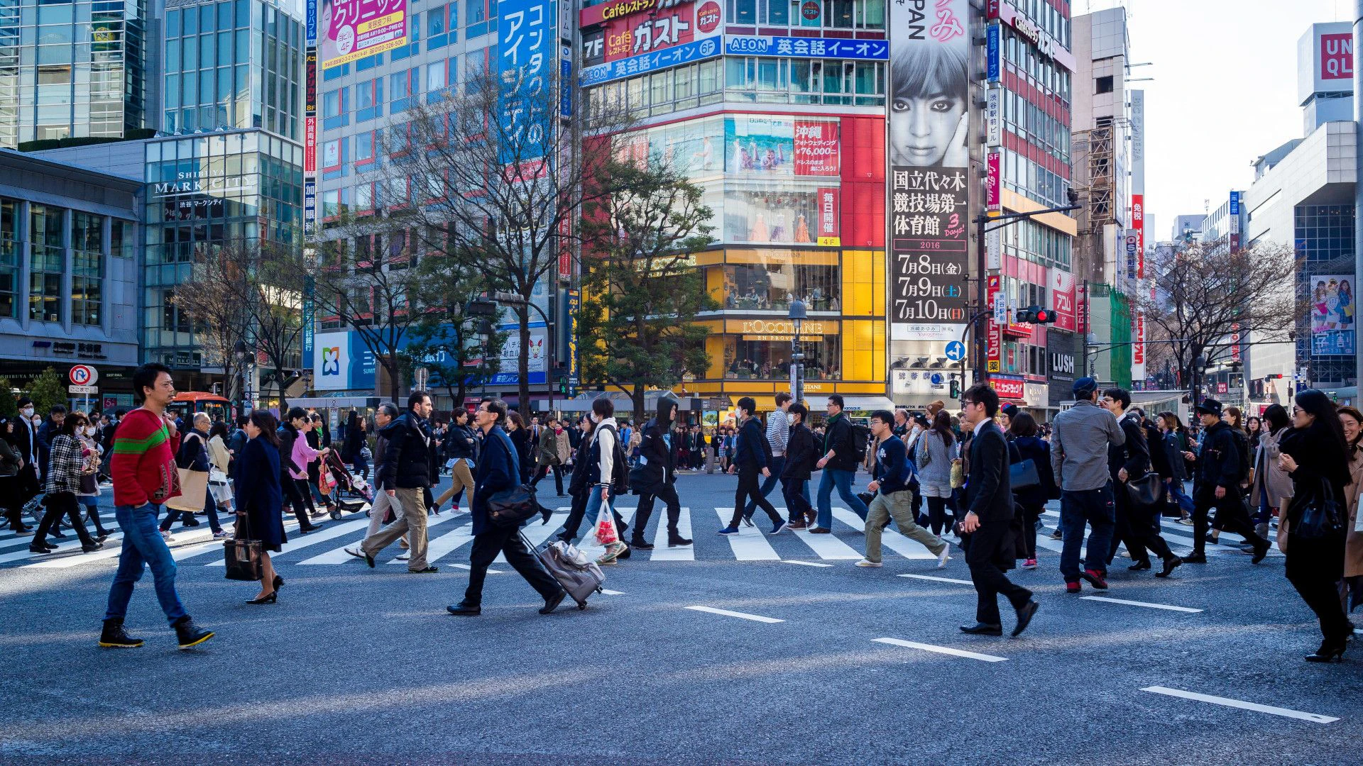 Des personnes en fin de journée traversent un carrefour à Tokyo.